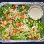 Caesar Salad in a catering foil tray with a dressing in a separate container