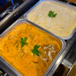 two catering foil containers one with chicken stroganoff and one with white rice