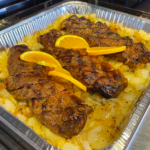 catering foil container with culotte steak on a bed of grilled onions oranges slices on top