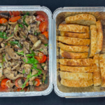 Two Foil catering containers one with sautéed mushroom and the other one with toasts