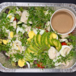 salad with avocados tomatoes boiled eggs and watercress in a catering foil tray dressing in a separate container