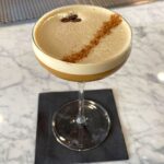 Espresso Martini on top of a black napkin on a marble counter top