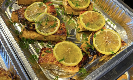 catering foil tray with grilled salmon fillets with slices of lemon